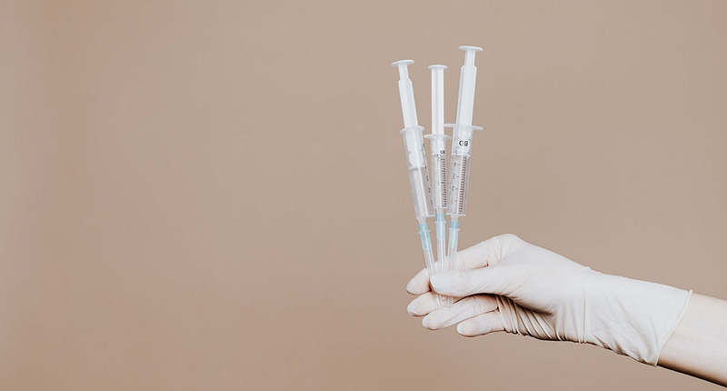 person holding three syringes with medicine
